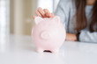 © Krakenimages.com - Young woman putting a coin inside piggy bank as savings for investment