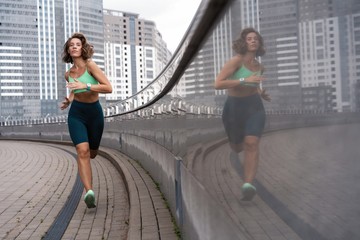 Sporty young woman athlete running on urban street in morning.