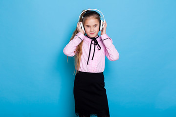 Wall Mural - Schoolgirl girl listens to music with headphones and dances