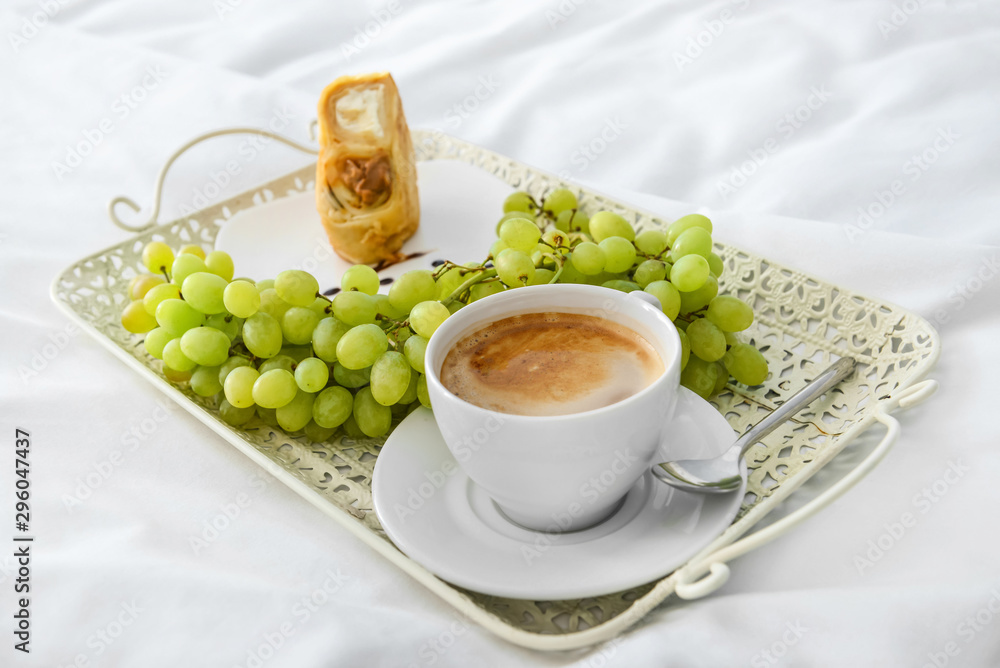 Tray with tasty breakfast on bed