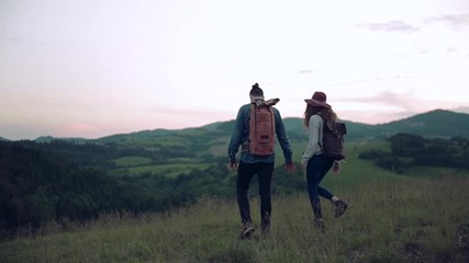 Wall Mural - rear view of young tourist couple travellers with backpacks hiking in nature.