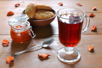 Wall Mural - A glass mug of black tea with a glass bowl of homemade peach jam on a wooden table. 