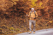 © Mediteraneo - Senior man hiking in autumn forest.