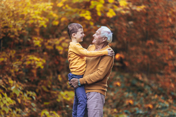 Wall Mural - Grandfather and grandson together in autumn park