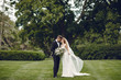 © prostooleh - Beautiful bride in a long white dress. Handsome groom in a black suit. Couple in a summer park