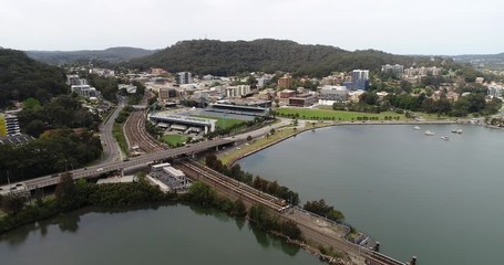 Sticker - Backward flying along railway wavebreak wall in Gosford town on Australian Central coast over Brisbane water bay.