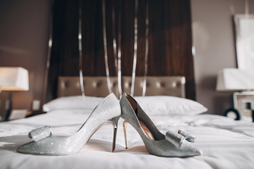 Bride's silver shoes. Elegant wedding shoes on a bed ina room