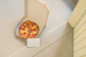 Wall Mural - Open box of pizza with empty card for text on home doorstep on front porch. Delivery. Concept