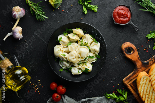 Fotografía Russian pelmeni meat Dumplings with greens in a black plate