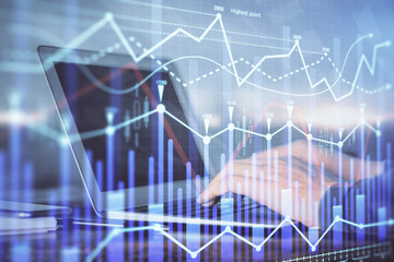 Double exposure of man's hands writing notes with laptop of stock market with forex graph background. Top View. Concept of research and trading.