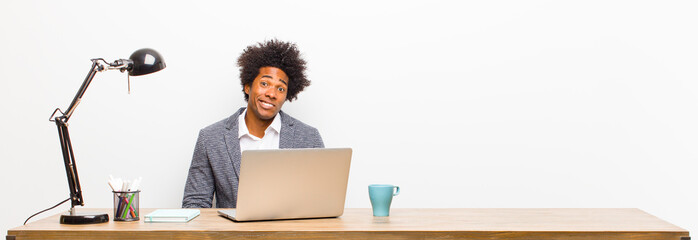 young black businessman looking puzzled and confused, biting lip with a nervous gesture, not knowing the answer to the problem on a desk