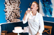 © the faces - pleasant girl in white apron eating yummy cupcakes, tasting cake in the kitchen. close up photo. copy space