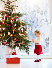 Wall Mural - Child decorating Christmas tree. Kid on Xmas eve.