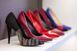 © fortton - Women's shoes in the store. Shoes of different colors presented on the trading shelf. A collection of high-heeled shoes standing on a shelf in a store.