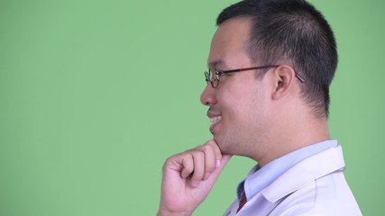 Wall Mural - Closeup profile view of happy Asian man doctor with eyeglasses thinking