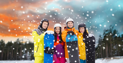 Sticker - leisure, extreme sport and people concept - happy friends in helmets with snowboards over winter forest background