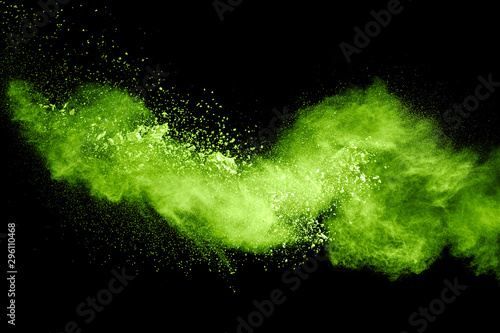Green yellow dust particles explosion on black background. Powder dust splash.
