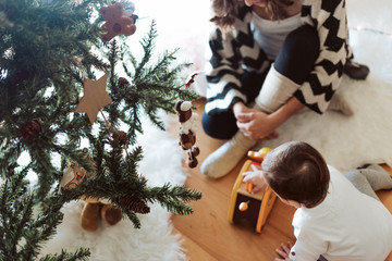 Wall Mural - Mother and baby playing around the Christmas Tree