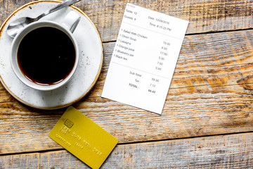 credit card for paying, coffee and check on cafe wooden desk background top view mock up