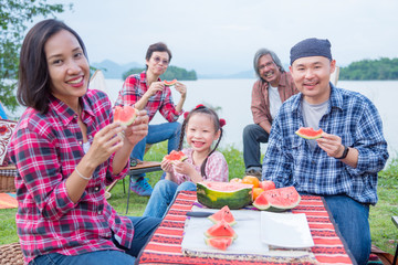 Wall Mural - Happy asian family camping and enjoy with watermelon together at camping site.