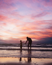 Father And Son Playing On The Beach At The Sunset Time.