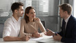 © fizkes - Confident manager consulting young couple about contract at meeting