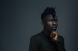 © Carlos David - Portrait of a serious young man with hand on chin, on dark black studio background