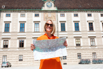 Young woman tourist stands with a city map on the background of the Hofburg courtyard in Vienna, Austria