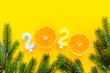 © 9dreamstudio - 2020 New Year design. Date laid out by candles near fir branches on yellow background top view frame copy space