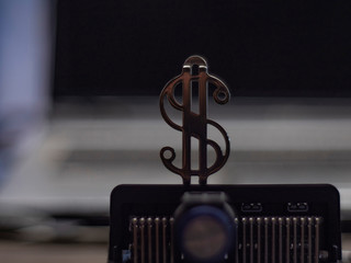 Metallic golden dollar sign on a chip on a laptop background . close-up metal dollar sign