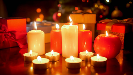 Wall Mural - Beautiful background with burning candles against glowing Christmas tree at night