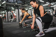 © estradaanton - Serious and concentrated young woman put some weight on barbell. Her asian friend repeat actions. They look down. Model prepare for exercise.