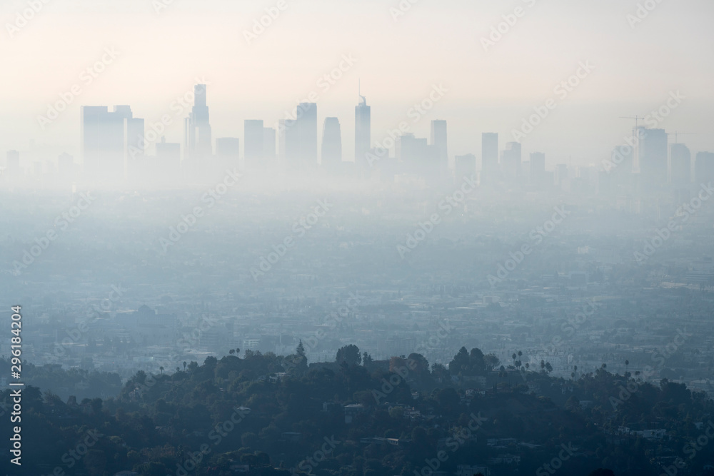 Thick layer of smog and haze from nearby brush fire obscuring the view of downtown Los Angeles buildings in Southern California.   Shot from hilltop in popular Griffith Park.   - obrazy, fototapety, plakaty 