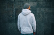 © San4ezz007 - City portrait of handsome hipster guy with beard wearing gray blank hoodie or hoody and hat with space for your logo or design. Mockup for print