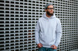 © San4ezz007 - City portrait of handsome hipster guy with beard wearing gray blank hoodie or sweatshirt and hat with space for your logo or design. Mockup for print