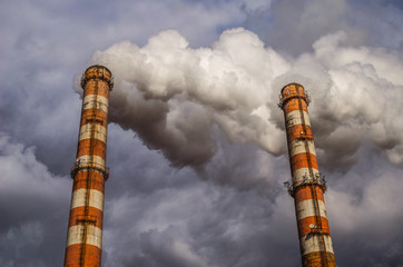 air pollution by smoke coming out of two factory chimneys. environmental issue related to air pollut