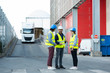 © auremar - three workers wearing high-visibility vests stood in factory loading bay