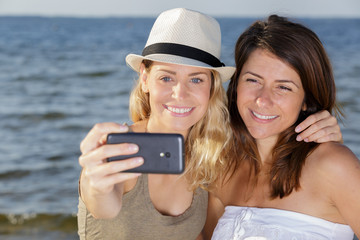 young female friends on vacation taking selfie on the beach