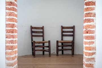 two brown school chairs with white wall on background in natural daylight