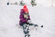 © benevolente - Little girl covered in snow sitting on sled with snobal in her hands in winter day. Happy child  playing with snow outdoors.