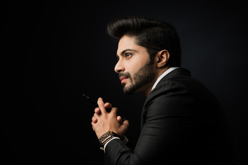 Wall Mural - Indian bearded Male businessman showing side profile, standing over black background