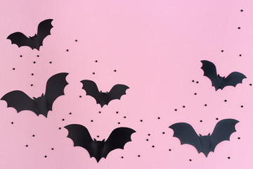 Flat lay with Black bats for halloween party. Paper decorations on pink background for holiday card or invitation. Copy space.