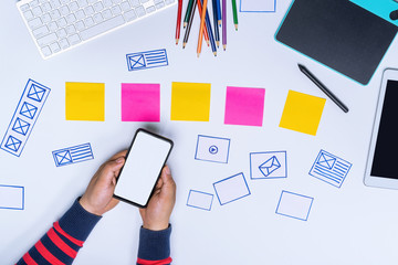 Wall Mural - ux designer hands holding white screen smartphone mockup on white office desk. user experience desig