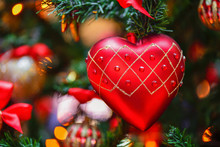 Christmas Toy  In The Shape Of A Red Heart Hanging On The Christmas Tree. Christmas Card, Background. Gorizontal Photo