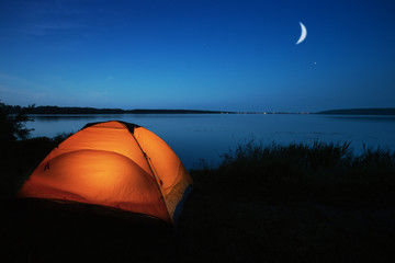 Wall Mural - orange tourist tent lit by a lake