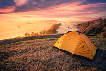 Wall Mural - orange tourist tent on hill above foggy river