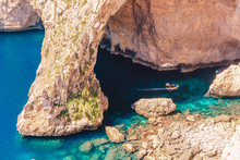 Blue Grotto In Malta. Pleasure Boat With Tourists Runs. Natural Arch Window In Rock
