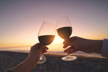 Couple of lovers drinking red wine during watching sunset and enjoying sea vacation at honeymoon