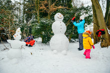 Young Family Building Snowman In Snowed Park. Little Toddler Girl Helping