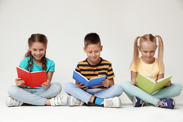 Wall Mural - Little children reading books on grey background